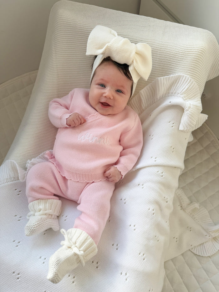 Pink baby kimono set on resting infant, ruffled collar and cream bow headband