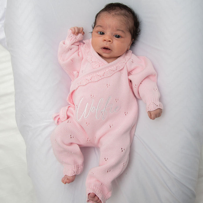 Pink pointelle kimono romper on baby with ruffled collar and embroidered name.