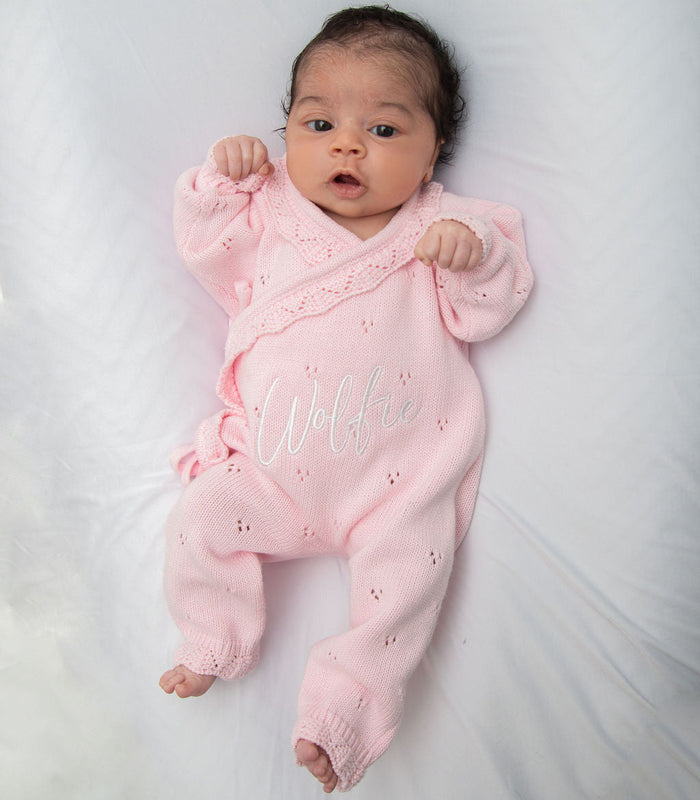 Pink pointelle kimono romper with ruffled cuffs and embroidered name on baby.