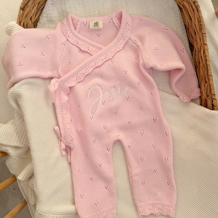 Pink pointelle kimono romper with cross-over lace trim and embroidered name.