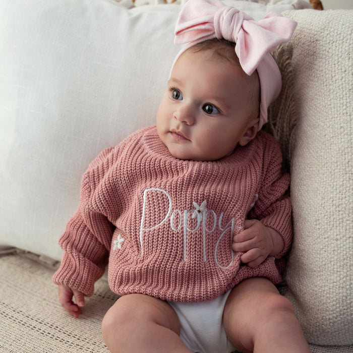 Pink knitted baby jumper with cursive 'Poppy' on the front, long sleeves