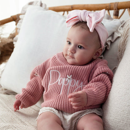 Pink knit baby jumper with 'Poppy' script on the chest and ribbed cuffs