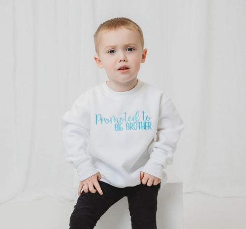 White sweatshirt with 'Promoted to BIG BROTHER' printed in blue lettering