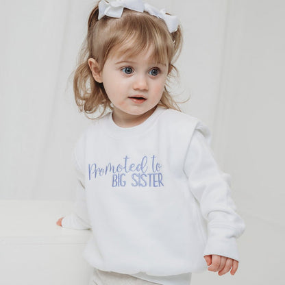 White pullover sweater with "Promoted to BIG SISTER" slogan on the front
