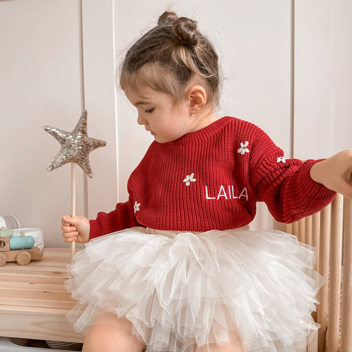 Red knitted jumper with white floral motifs and LAILA lettering, long sleeves