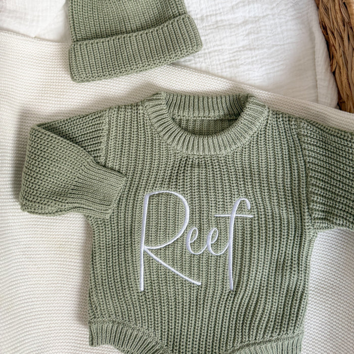 Sage green knit romper with long sleeves and embroidered cursive name on chest