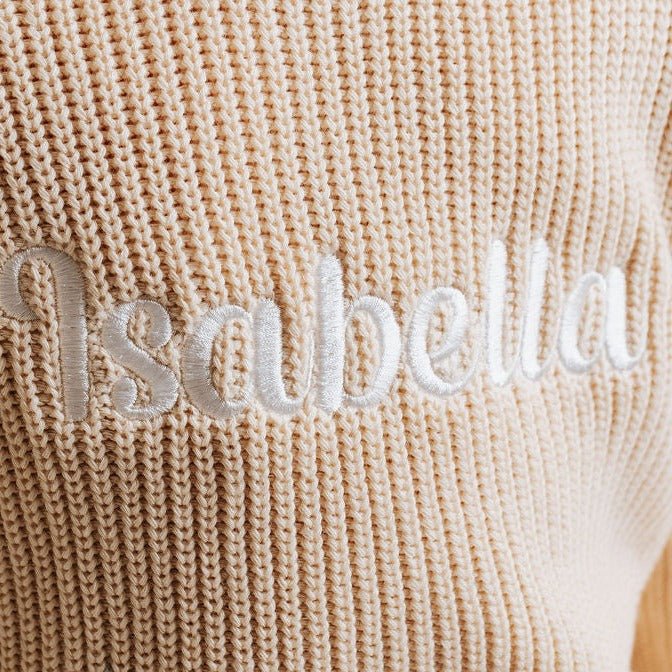 Beige knitted jumper with raised applique name "Sandbelle" across chest