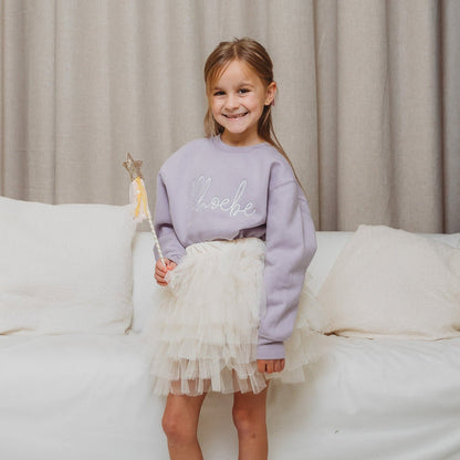 Lavender crewneck sweatshirt with white script embroidery, paired with white tulle skirt