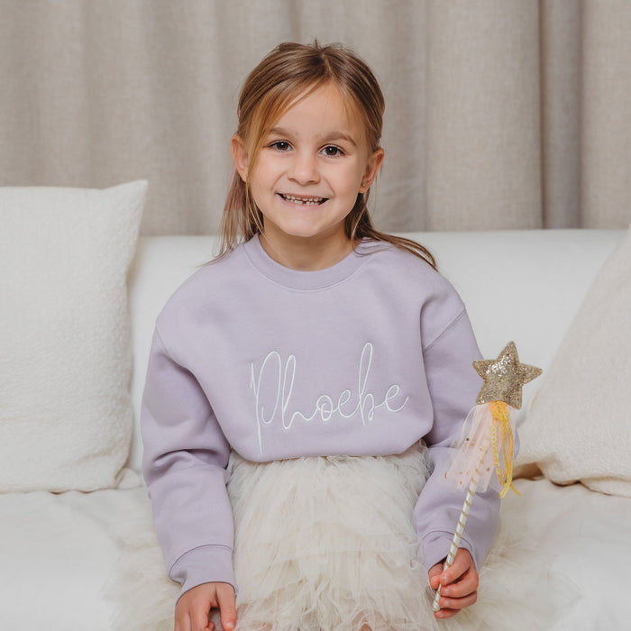 Lavender crewneck sweatshirt with white script embroidery, worn with white tulle skirt