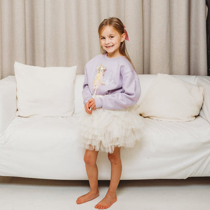 Lavender crewneck sweatshirt with white script embroidery, tulle skirt, holding star wand