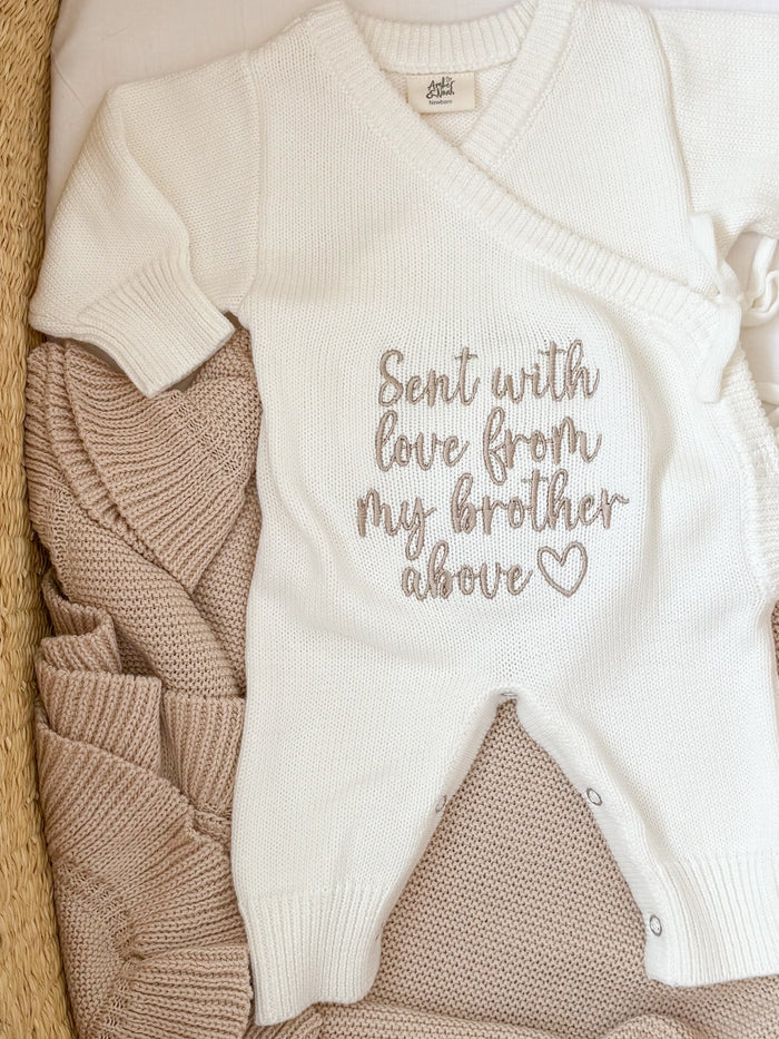 Cream knitted baby romper with embroidered message text and tan foot panel
