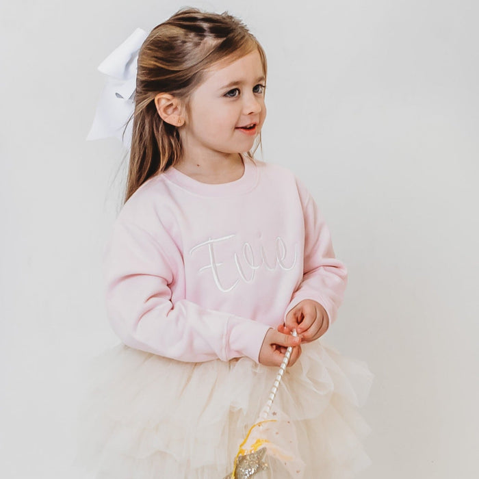 Light pink embroidered sweater with long sleeves, crew neck, and script design