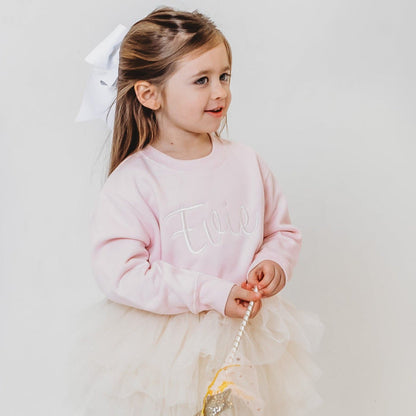 Light pink embroidered sweater with long sleeves, crew neck, and script design