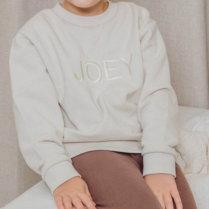 Light stone crewneck sweater close-up with long sleeves and JOEY embroidery