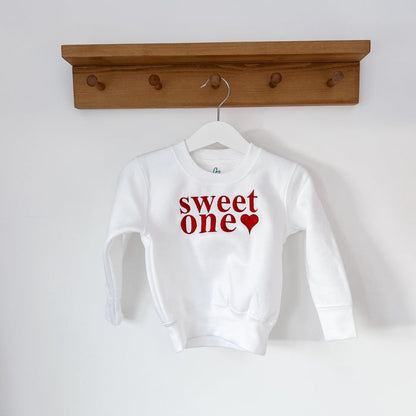 White crewneck sweatshirt with 'sweet one' red heart graphic