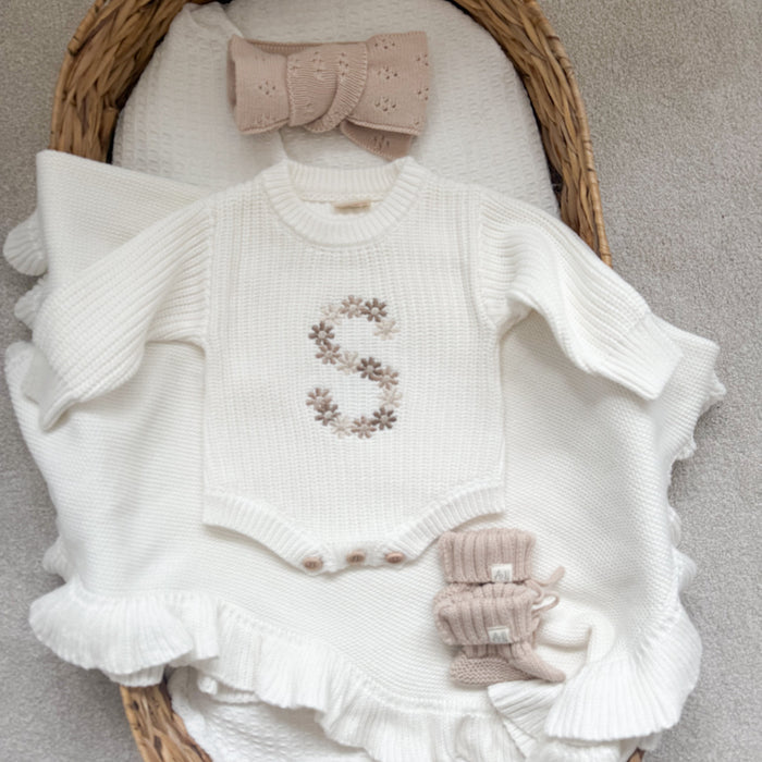 White knitted baby romper with floral initial embroidery, ruffled cuffs, and knit booties set
