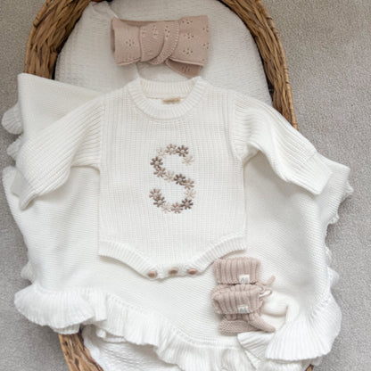 White knitted baby romper with floral initial embroidery, ruffled cuffs, and knit booties set
