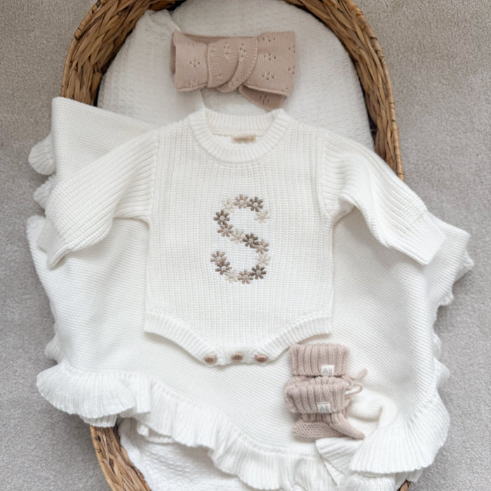 White knitted baby romper with embroidered floral initial and matching knit booties