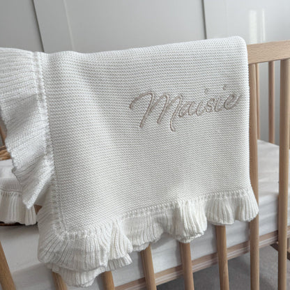 White knitted blanket with frill hem and embroidered script name on center