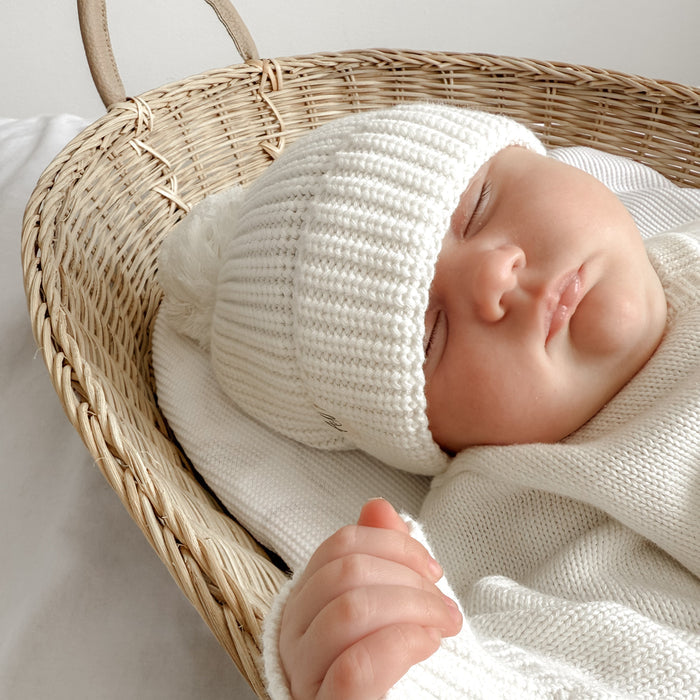White knitted baby hat with ribbed texture and pom-pom, snug fit