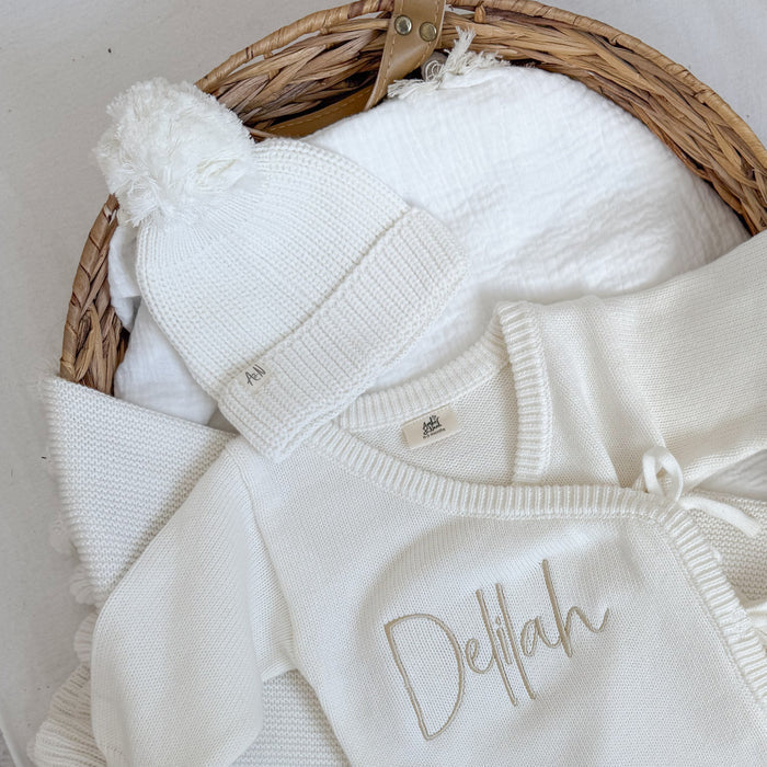 White knitted baby hat with ribbed brim and white pom-pom