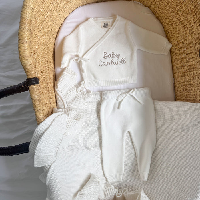 White baby kimono set: 'Baby Cardwell' knit top, pants, folded socks, and hat