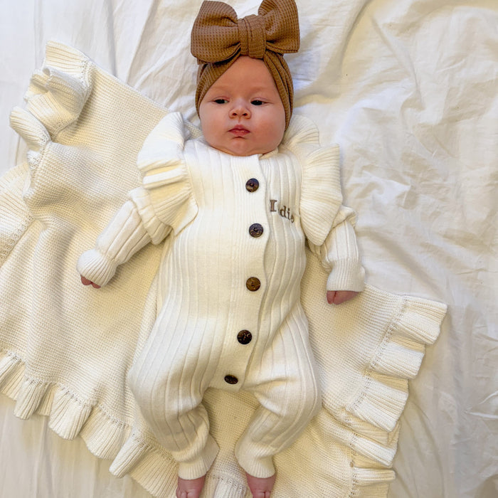 White knit romper with frill sleeves and button front, worn with brown headtie bow