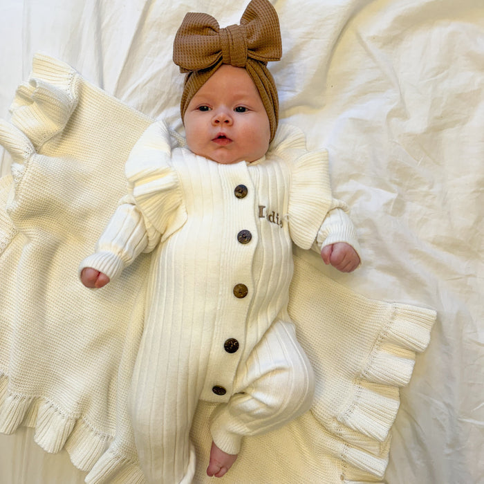 White knit romper with frill sleeves, button front, and brown bow headtie