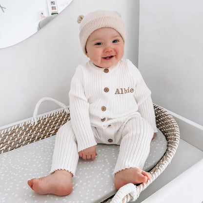White long-sleeve romper with ribbed texture, button placket, and embroidered name