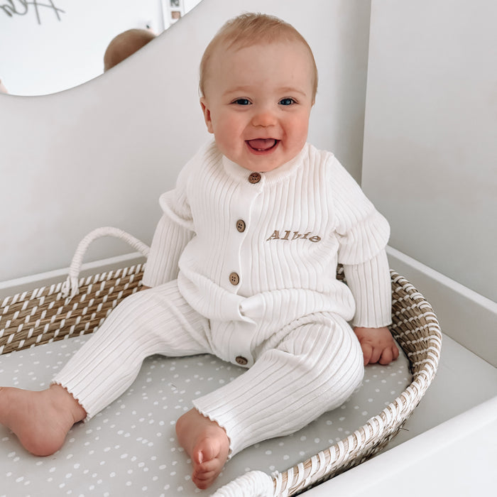White long-sleeve romper with snap buttons and embroidered name on chest