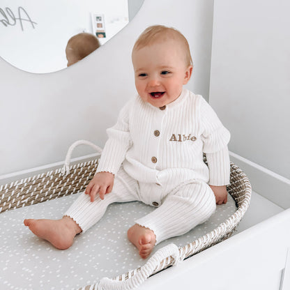 White long-sleeve romper with button front and embroidered name, striped ribbed knit