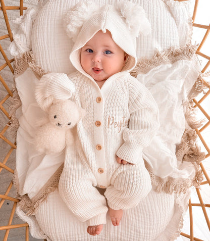 White knit pom pom romper with hood, long sleeves, and wooden-look button front