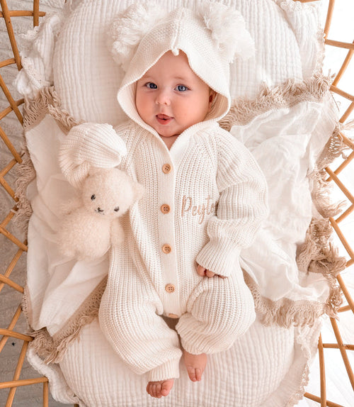 White knit pom pom romper with hood, long sleeves, and wooden-look button front