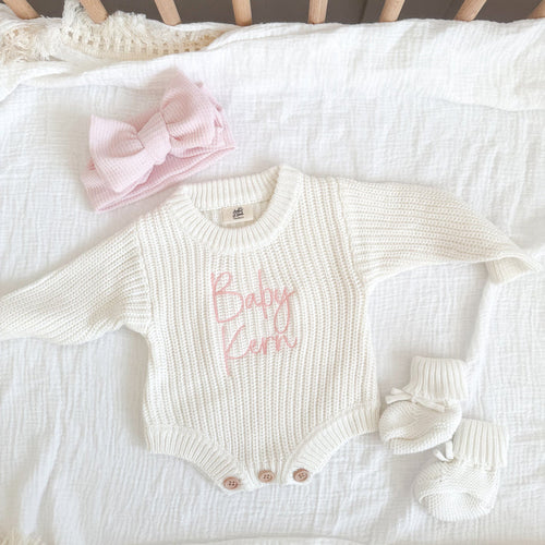 White knitted baby romper with pink name print, cuffed sleeves and snap buttons