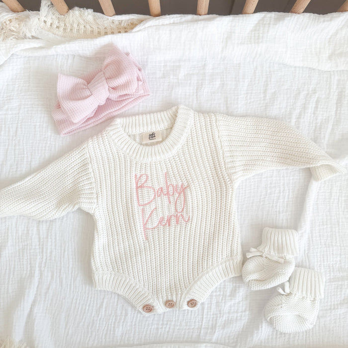 White knitted baby romper with pink name print, cuffed sleeves and snap buttons