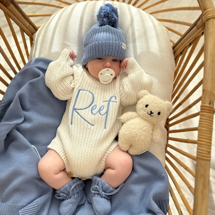 Cream knitted romper with blue 'Reef' print and blue pom knit hat, plush rabbit