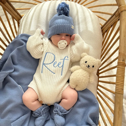 Cream knitted romper with blue 'Reef' print and blue pom knit hat, plush rabbit
