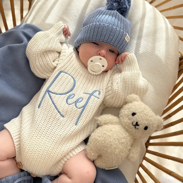 Cream knitted romper with blue 'Reef' print and blue knit pom hat, plush rabbit