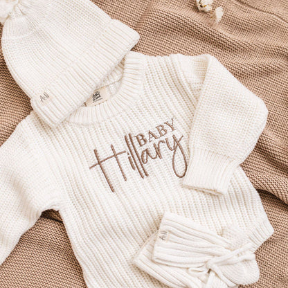 White knitted baby romper with embroidered "Baby" name and snap buttons