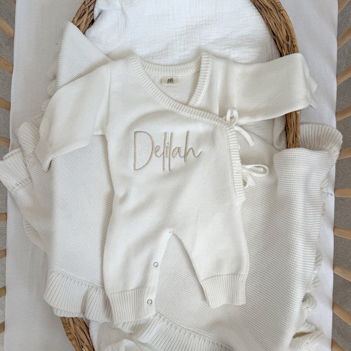 White long romper with Delilah name embroidery, hood, and snap button closures