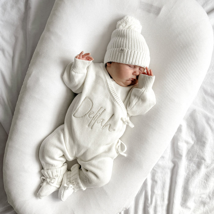 White long romper with Delilah embroidery worn with a matching knit hat