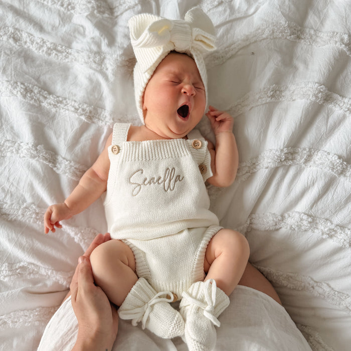 White knit personalised romper with front script name, bow top and ruffle leg cuffs