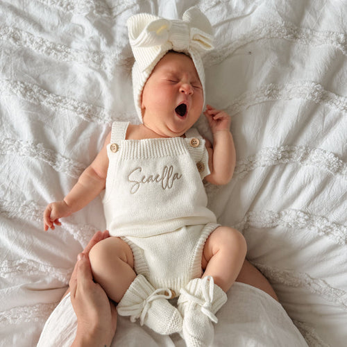 White knit personalised romper with front script name, bow top and ruffle leg cuffs