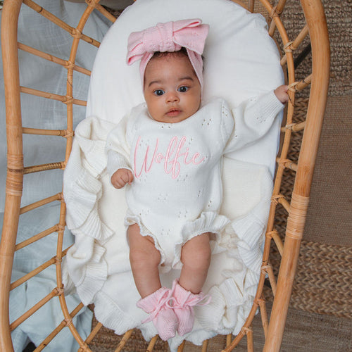 White knit baby romper with pointelle sleeves and pink bow headband
