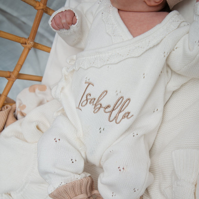 White pointelle kimono romper close-up with “Isabella” embroidery and textured knit pattern.