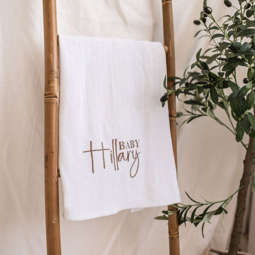 White knitted baby blanket with embroidered 'Baby Mary' text