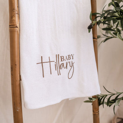Close-up of white knitted baby blanket with embroidered 'Baby Mary' name