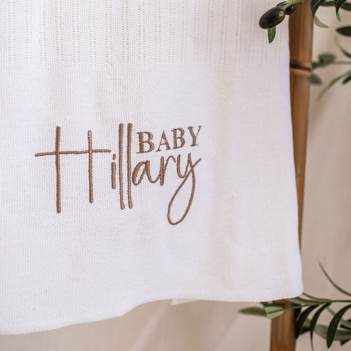 Close-up of 'Baby Mary' embroidery on white knitted baby blanket