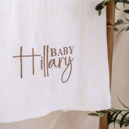 Close-up of 'Baby Mary' embroidery on white knitted baby blanket