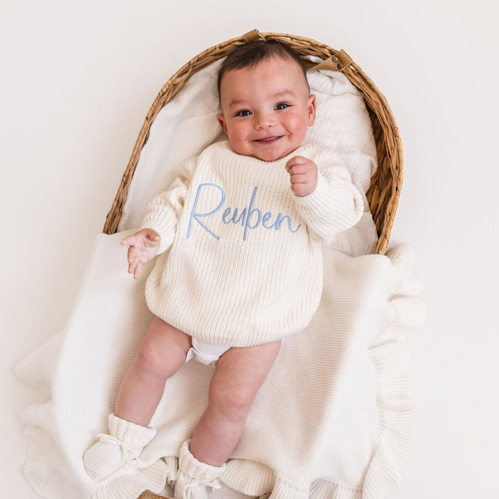 Personalized knitted baby jumper in white with blue script 'Reypen' on front
